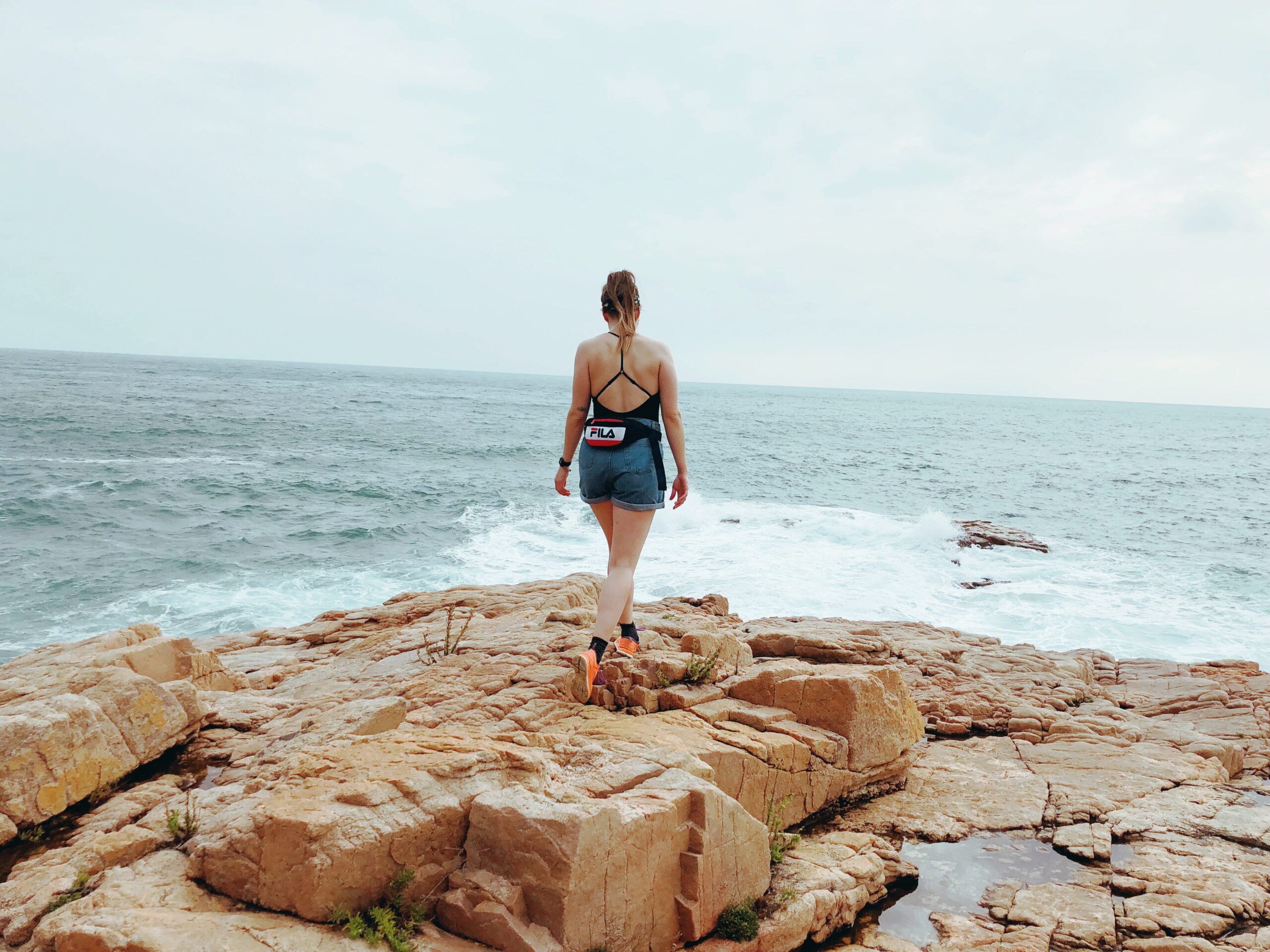 Sæunn of SajaRut Yoga walking on a cliff overlooking the ocean.
