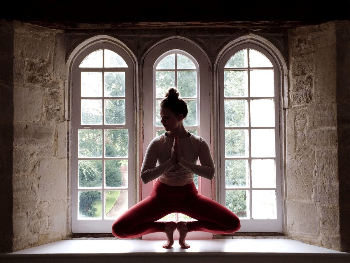 power SajaRut Yoga teacher Sæunn in a toestand pose in a rustic window